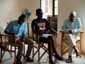 Balele kafumu kutoka Chuo kikuu cha Dar es Salaam akimhoji Msimamizi wa kituo cha Pangarithi Ismail Mwishashi kwenye mahojiano maalumu ya Pangani FM radio.  Balele Kafumu of the University of Dar es Salaam interviews the Supervisor of the Pangarithi Heritage Centre, Ismail Mwishashi, for Pangani FM radio. (Photo: L. Meghan Dennis)