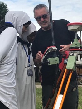 (Figure 3. Nick Pearson showing the GPS and base station to two students from a local school who where learning a method called chain surveying!)